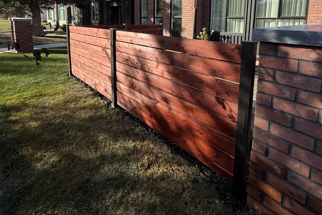 Red cedar horizontal slat privacy fence with steel posts installed in a Calgary backyard by All The Moore Landscaping