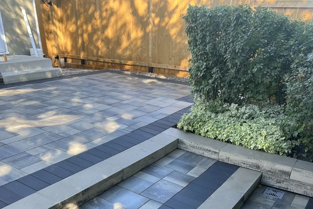 Two-tone paver patio with broad steps and mulched planting beds, Calgary