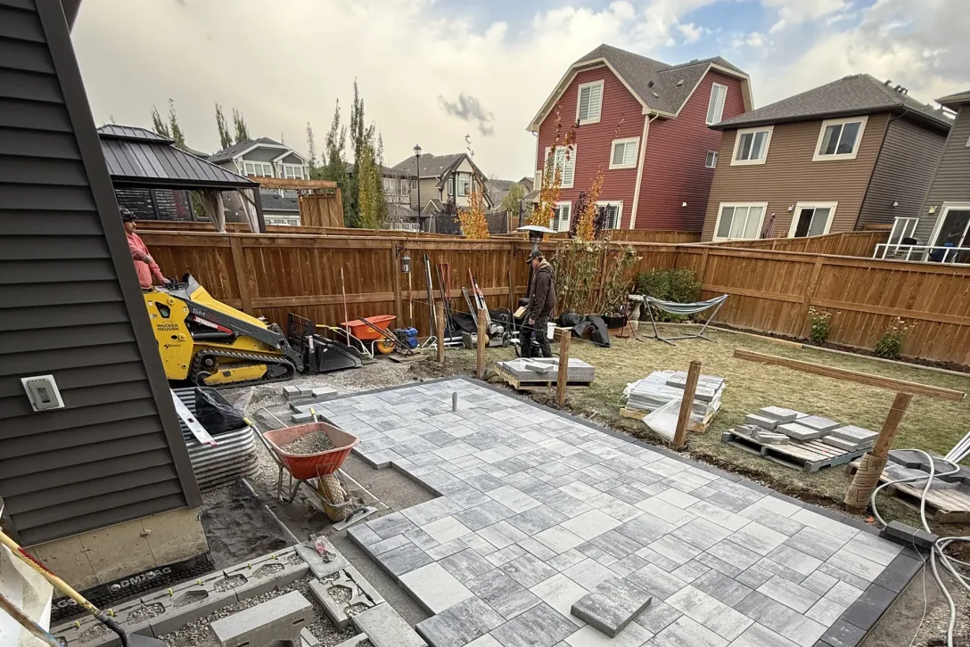 All The Moore Landscaping crew installing an interlocking paver patio with a mini-skid steer in Calgary