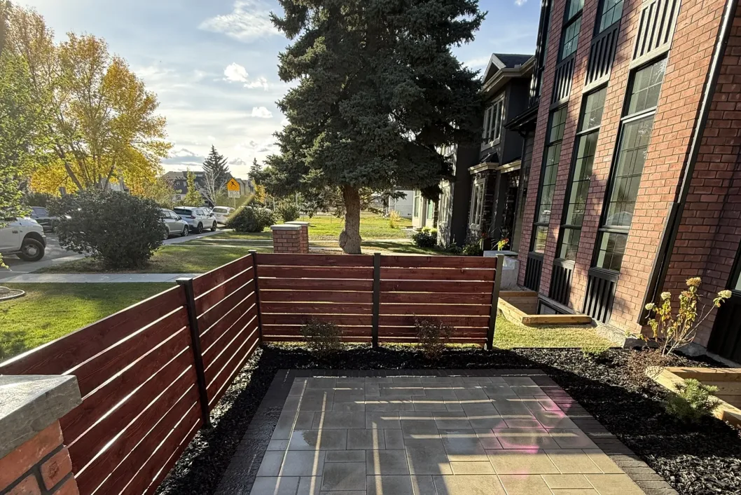 Modern horizontal cedar privacy fence with interlocking paver patio and garden beds, Calgary