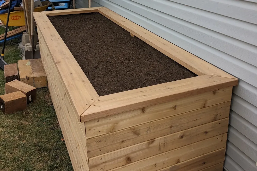 Cedar raised planter box with fresh soil and corner joinery detail, Calgary