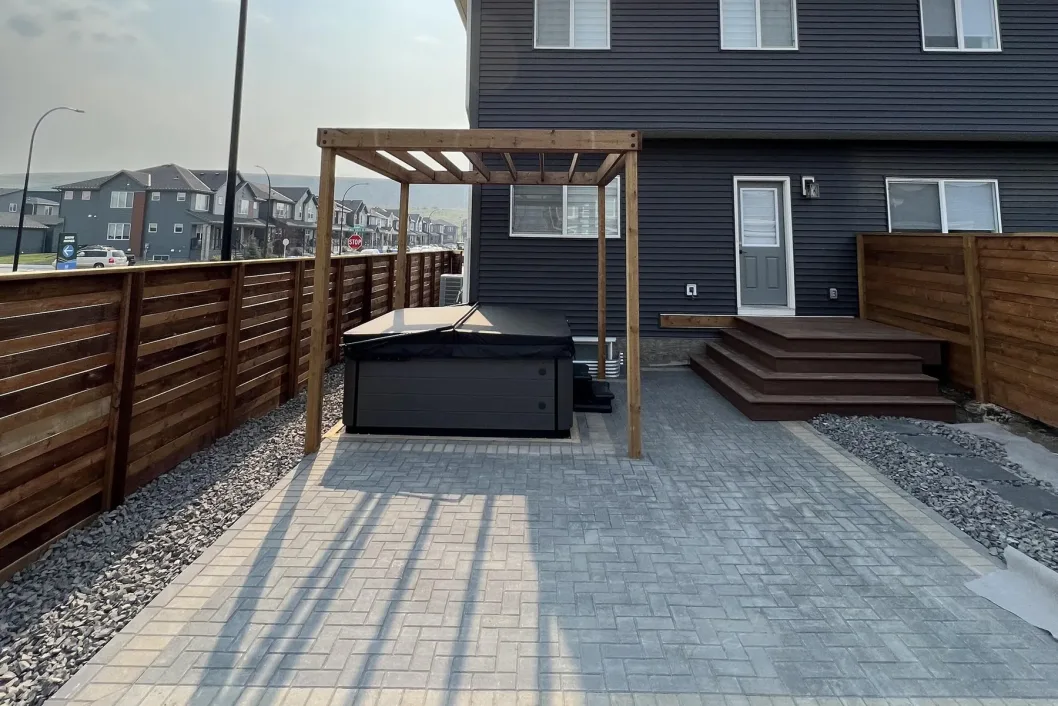 Hot tub patio with cedar pergola and modern dark-siding home, Calgary