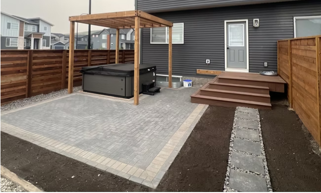 Paving stone patio with pergola and hot tub in a newly built backyard in Calgary
